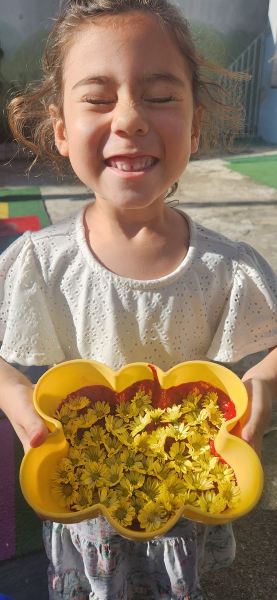 Menina sorrindo com flores num potinho